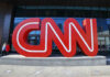 Large red CNN sign outside building entrance.