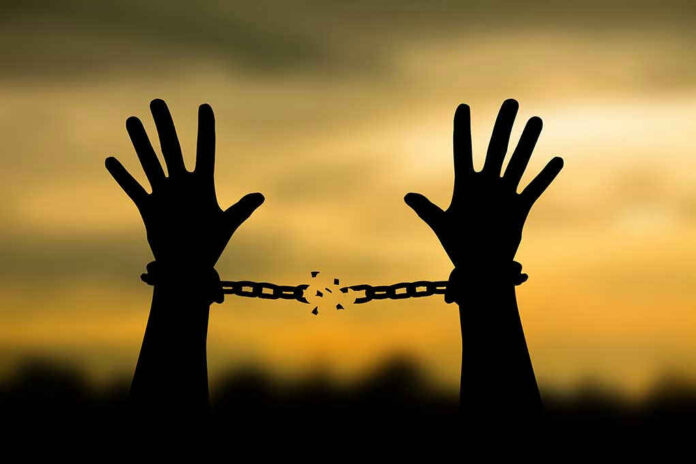 Hands breaking free from chains at sunset.