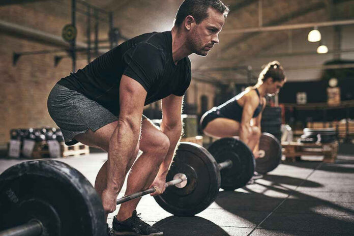 Man and woman lifting barbells in gym.
