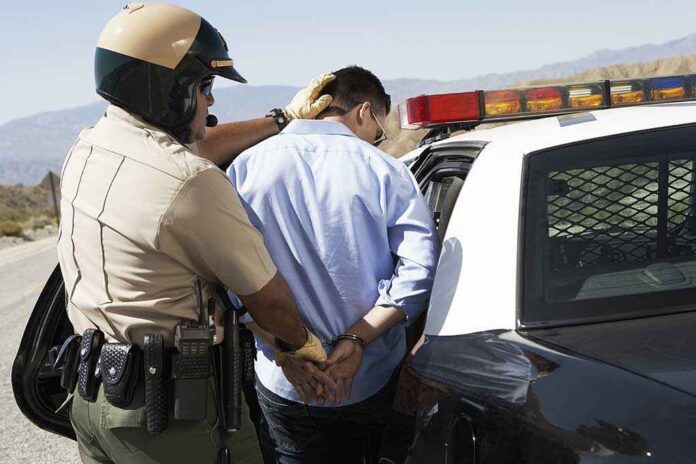 Police officer arresting a suspect near a patrol car