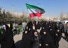 Coup Power Grab Shakes Tehran – Regime SCRAMBLING! Group of women in black attire marching with an Iranian flag