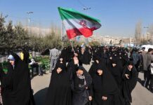 Group of women in black attire marching with an Iranian flag
