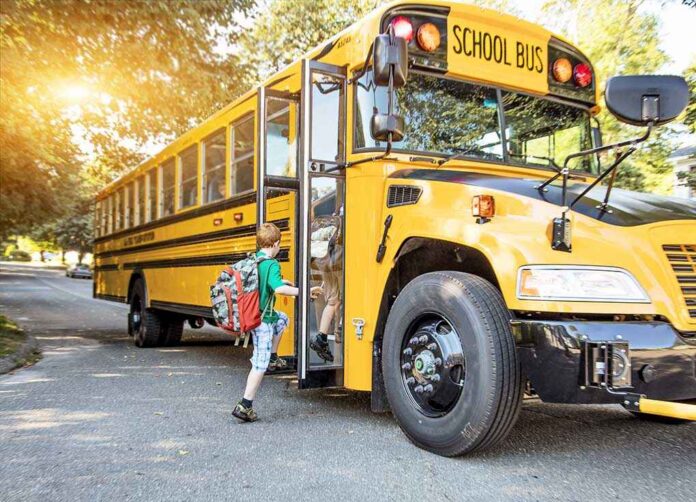 A child with a backpack boarding a yellow school bus