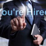 Businessman pointing at a digital display that says 'You're Hired'