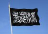 Black flag featuring Arabic script against a blue sky
