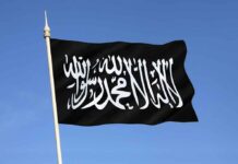 Black flag featuring Arabic script against a blue sky