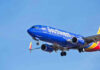 Airline Issues SHOCKING Ban: What’s Next? Southwest Airlines plane flying in blue sky.
