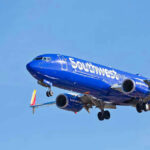 Airline Issues SHOCKING Ban: What’s Next? Southwest Airlines plane flying in blue sky.
