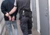 Officer escorting handcuffed person down hallway.