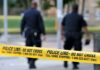 Police officers walking past caution tape at a crime scene
