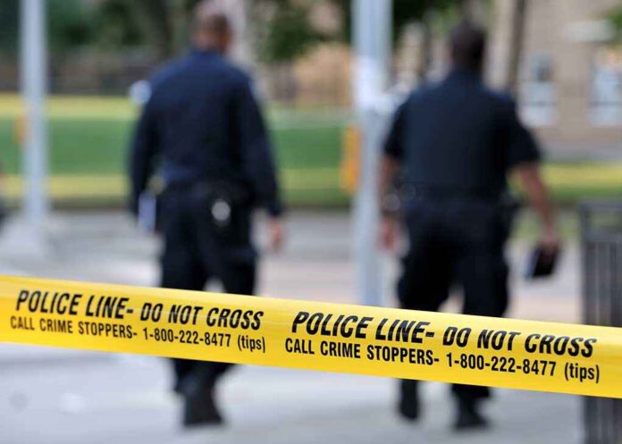 Toronto-july,17:,Police,Line,Do,Not,Cross,Tape,With,Two Police officers walking past caution tape at a crime scene