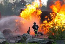 Fire CHAOS: 30,000 Flee – Shocking Devastation! Firefighter battling a large fire with water spray