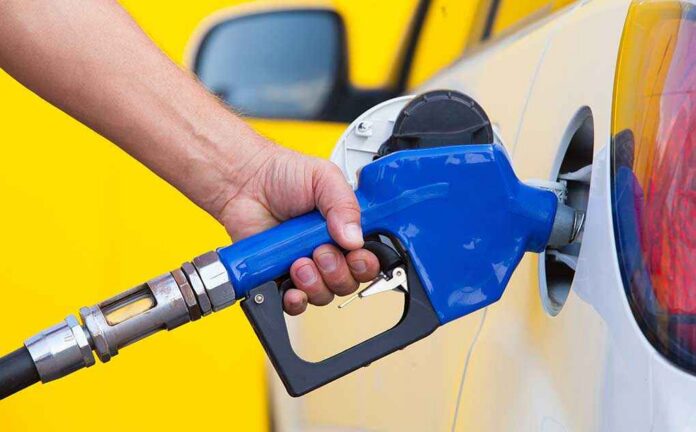 Pumping,Gas,At,Gas,Pump.,Closeup,Of,Man,Pumping,Gasoline A person refueling a car at a gas station with a blue nozzle