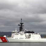 A U.S. Coast Guard ship docked under cloudy skies