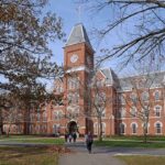 BOYCOTT BOMBSHELL: Black Athletes in Political Crossfire! Historic university building with students walking in front during autumn