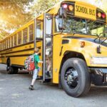 A child with a backpack boarding a yellow school bus
