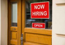 A door with a 'Now Hiring' sign and an 'Open' sign