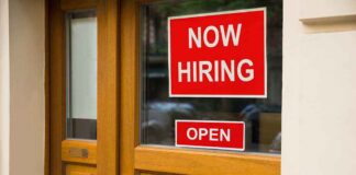 A door with a 'Now Hiring' sign and an 'Open' sign