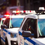 Police cars with flashing lights in line formation.