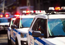 Police cars with flashing lights in line formation.