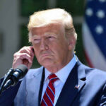 Trump Declares Iran War ENDED During Call Man in a suit adjusting an earpiece.