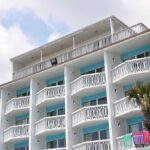 Fire RIPS Through Resort – 1,700 FLEE! Exterior view of a beachfront hotel with balconies and colorful towels hanging