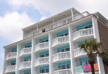 Fire RIPS Through Resort – 1,700 FLEE! Exterior view of a beachfront hotel with balconies and colorful towels hanging