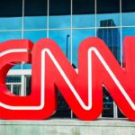 Large red CNN logo in front of a glass building