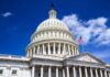 The U.S. Capitol building with a dome and American flag against a blue sky