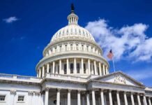 The U.S. Capitol building with a dome and American flag against a blue sky