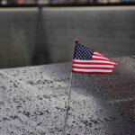 9/11 Families Revolt: Muslim Mayor Not Welcome American flag on a rainy memorial nameplate.