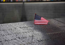 9/11 Families Revolt: Muslim Mayor Not Welcome American flag on a rainy memorial nameplate.