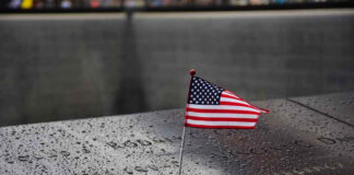 American flag on a rainy memorial nameplate.