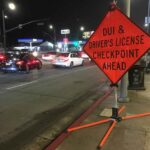 Famed NFL Broadcaster ARRESTED! Traffic checkpoint warning sign on city street at night