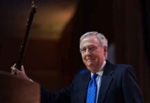 Hospital Photo Sparks McConnell Mystery A political figure smiling while holding a microphone