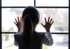 Pure Evil Inside House – 14 Children RESCUED! A child with long hair presses their hands against a window, looking outside