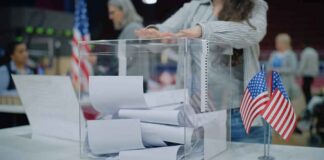 Person casting a ballot into a clear box at a polling station