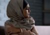 Woman in headscarf looking to the side with arms crossed