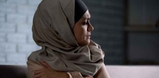 Woman in headscarf looking to the side with arms crossed