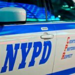 NYPD patrol car side with blue stripe and door lettering