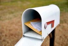 White mailbox with red flag holding envelopes and padded mailers