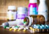 AIDS-Era Ban Faces Shocking Reboot Medicine pills and syringe on table with brown bottle