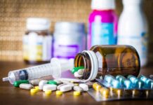Medicine pills and syringe on table with brown bottle