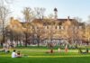 Students relaxing on a campus quad in front of a brick academic building