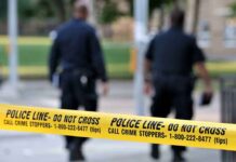 Police officers walking past caution tape at a crime scene