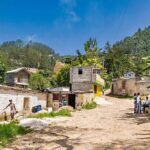Rural village street with people gathered and hills in the background