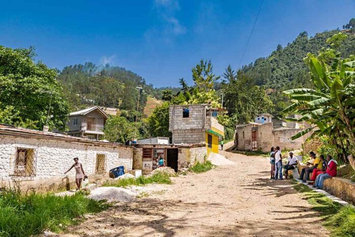 Rural village street with people gathered and hills in the background