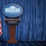 White House press briefing podium with U.S. flag and blue curtain