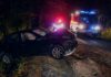 Crashed car on a dark roadside with emergency vehicles