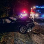 Crashed car on a dark roadside with emergency vehicles